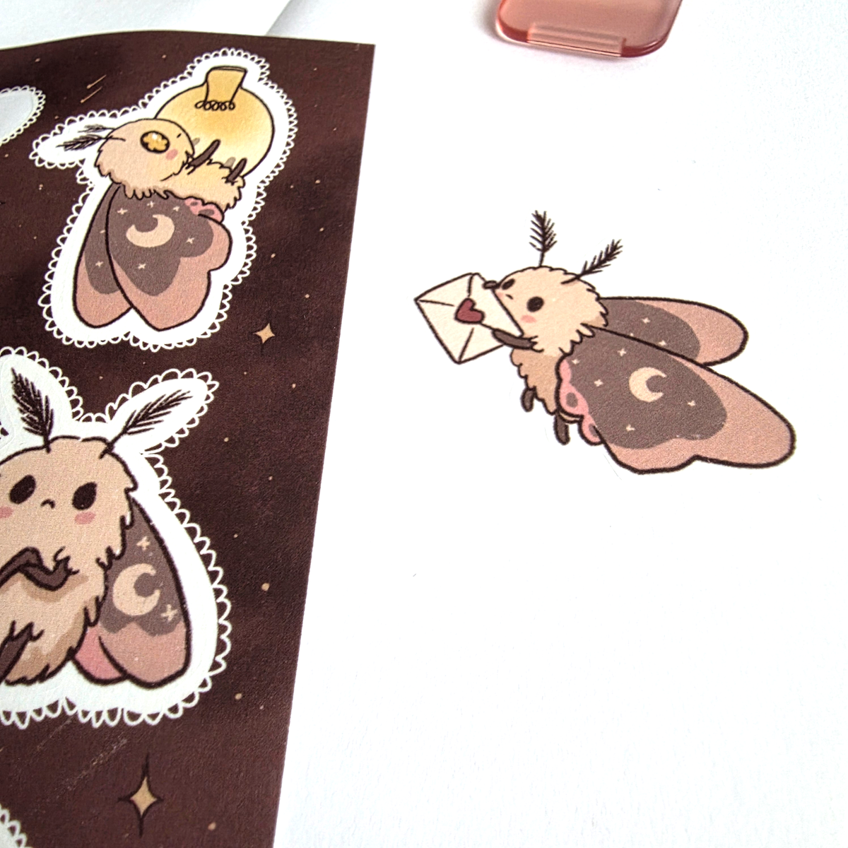 Close-up of a moth washi sticker carrying a heart-sealed letter